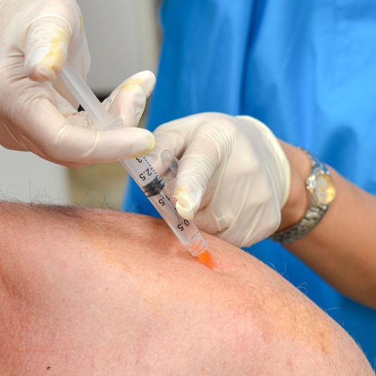 doctor injecting platelet-rich plasma into patients shoulder