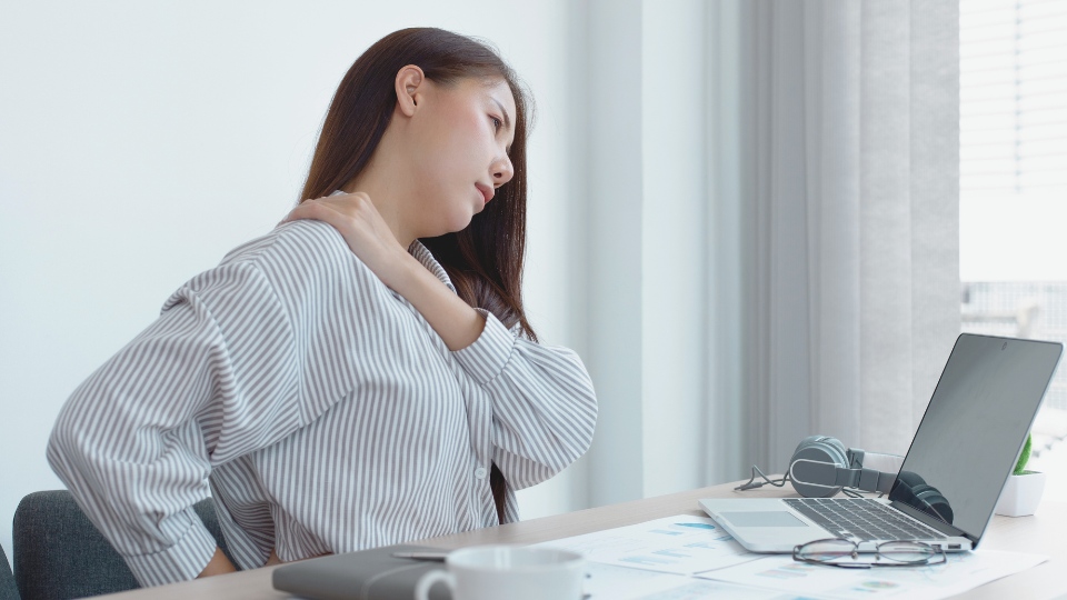 woman with shoulder pain at her laptop